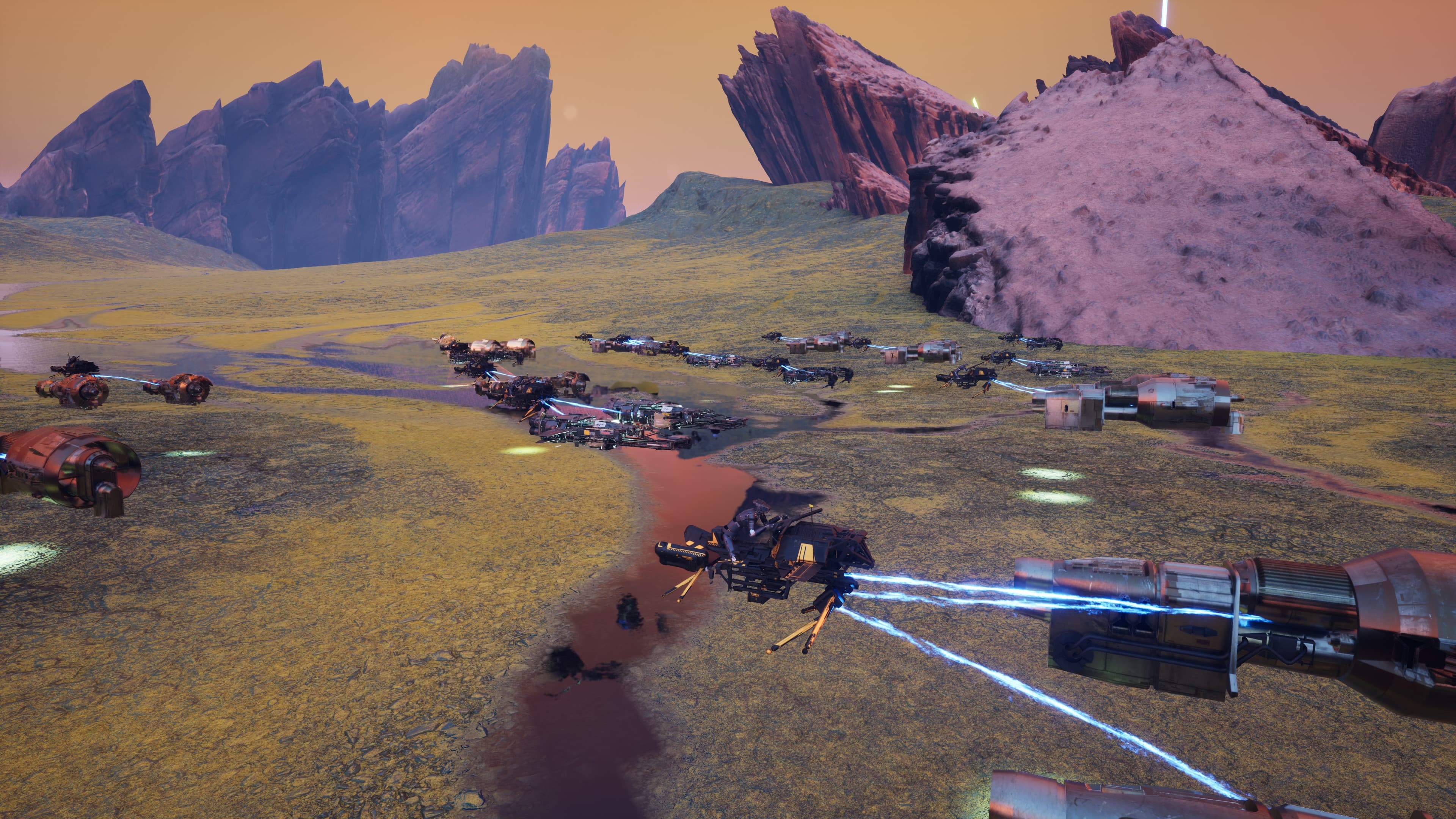 A pack of combat racers crossing a rocky alien plain beneath jagged mountains.