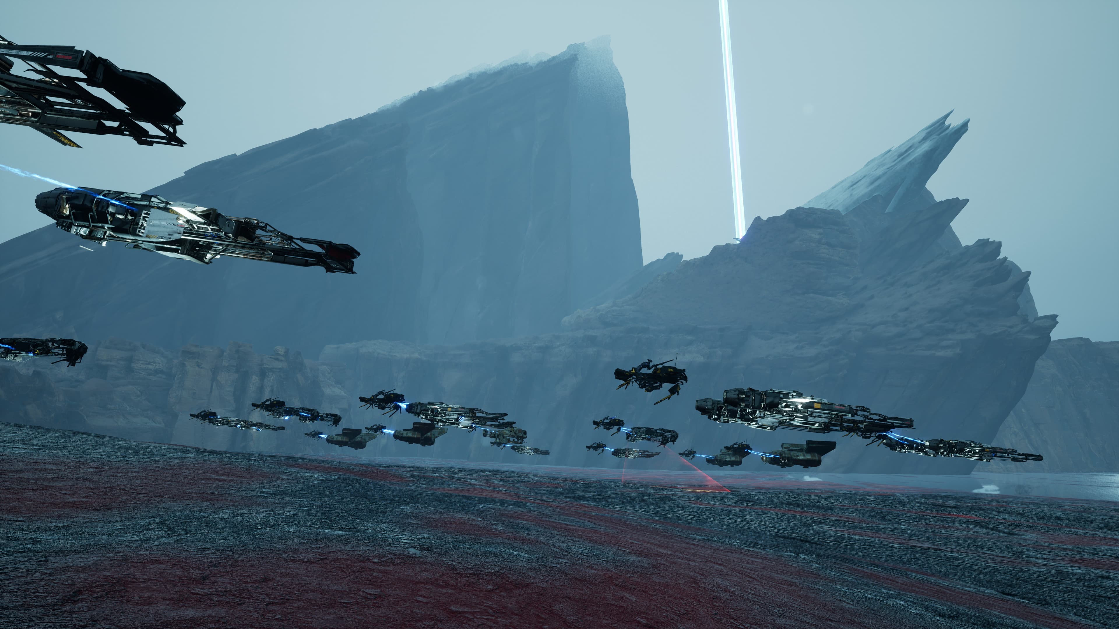A large pack of racers speeding beneath towering rock formations.